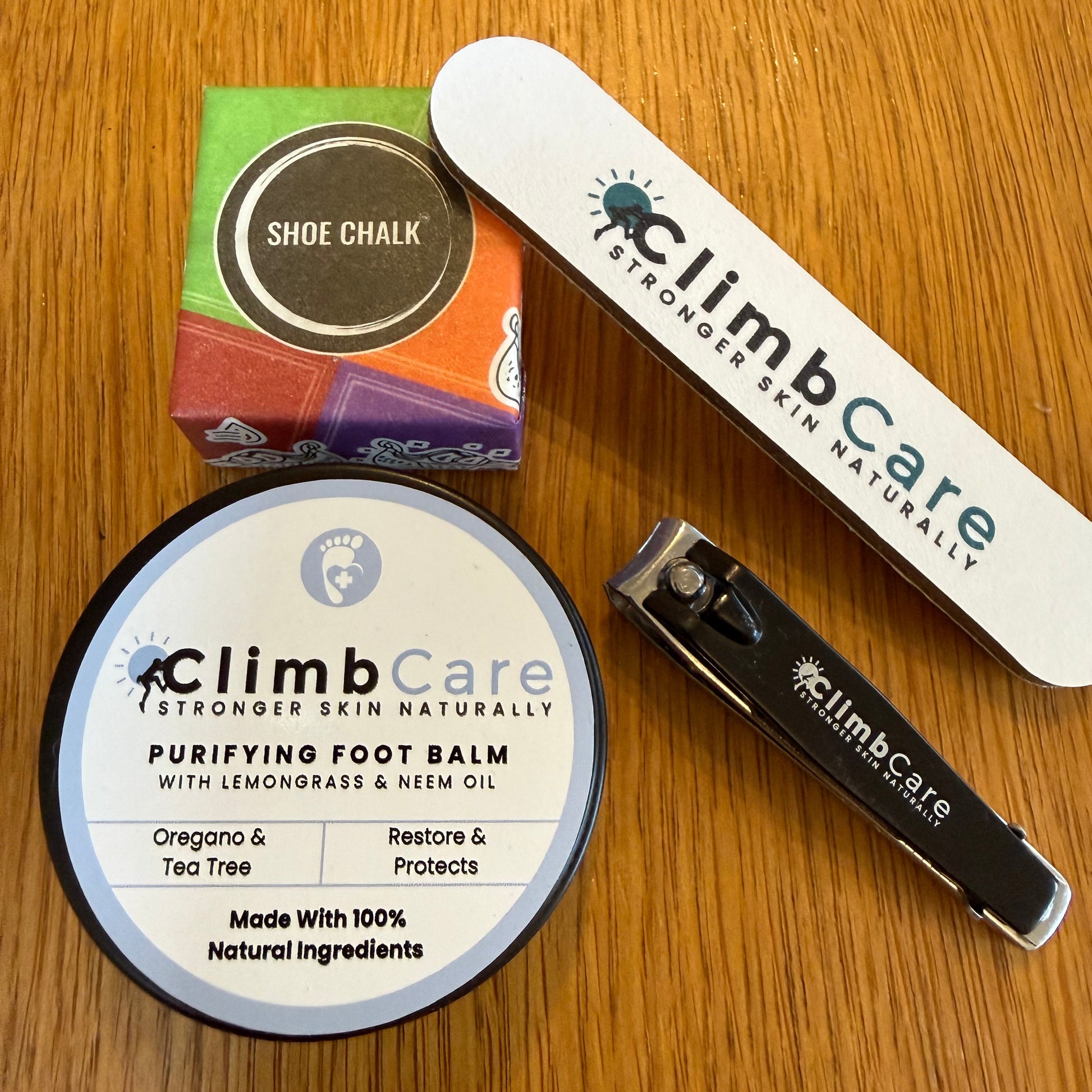 ClimbCare skincare products including balm, nail file, and shoe chalk on a wooden surface.