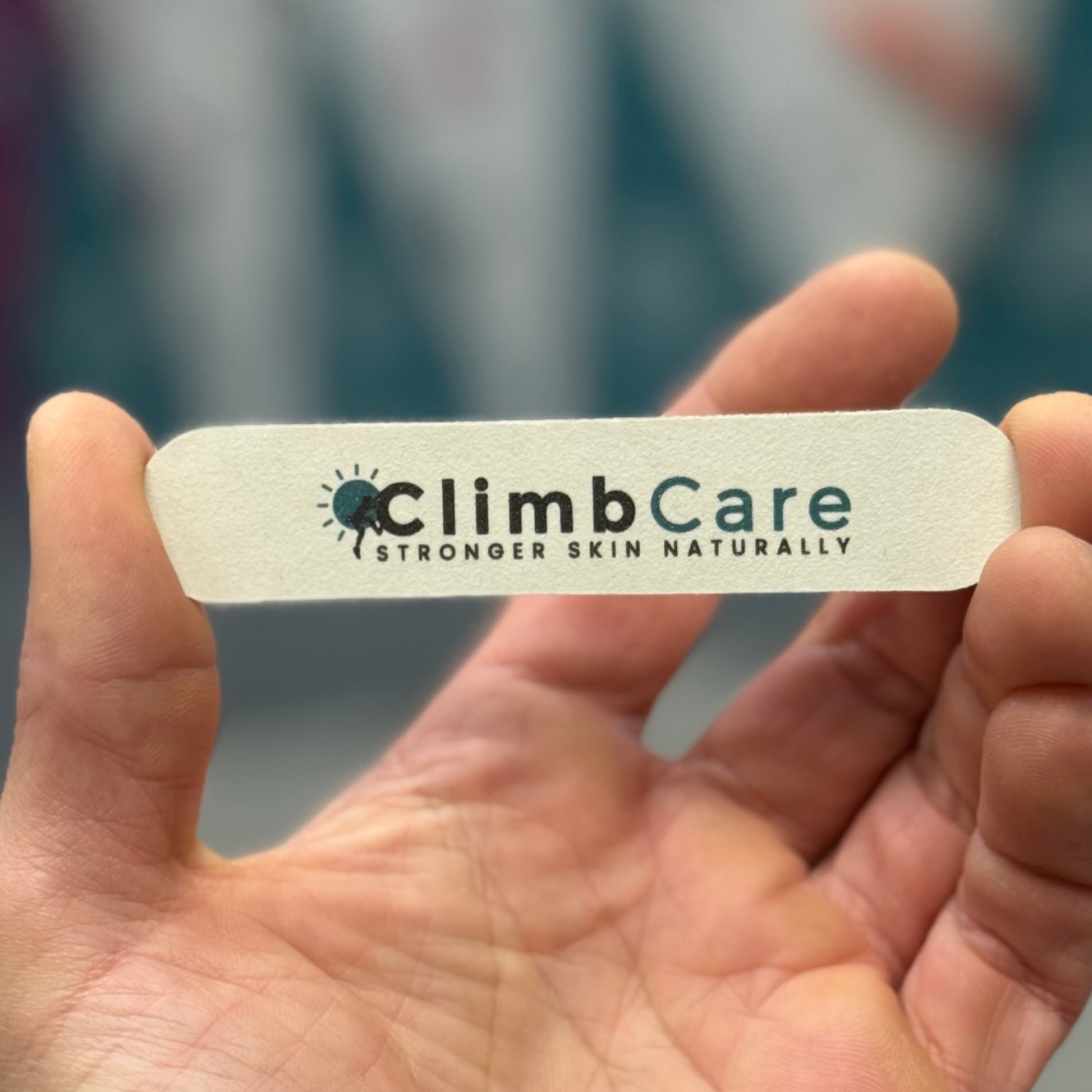 Hand holding a ClimbCare skin & Naiil file with a blurred background